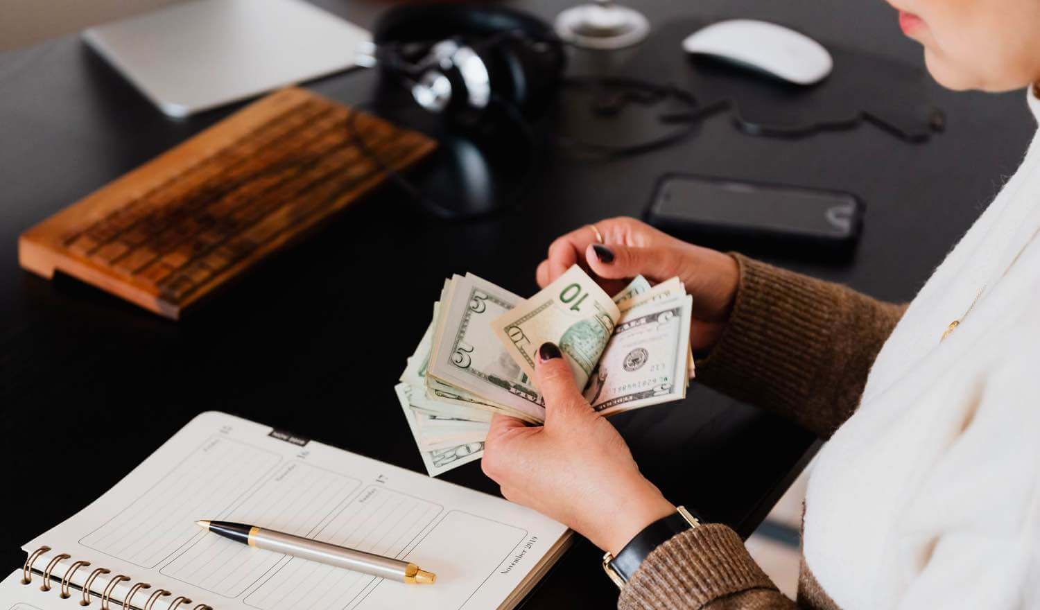 A woman flipping throguh cash and writing in a book